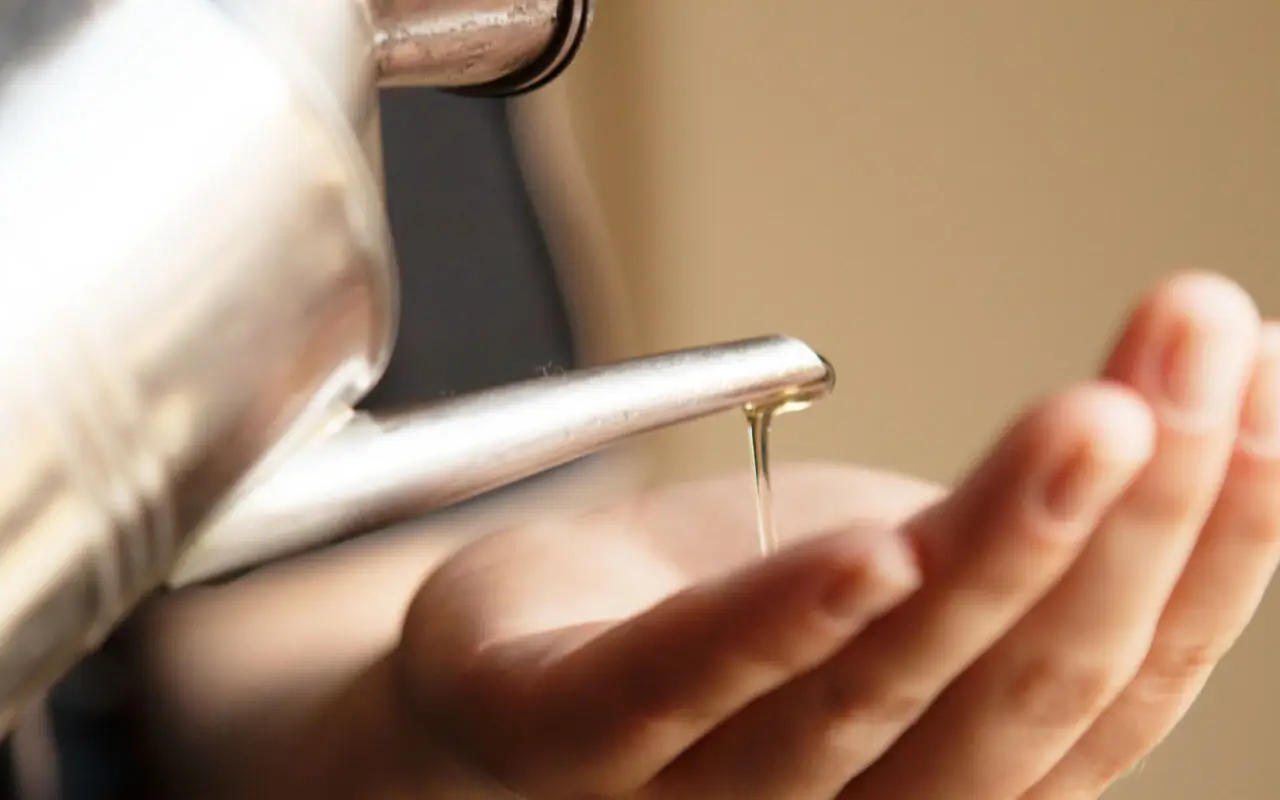 A person pouring liquid into their hand indoors.