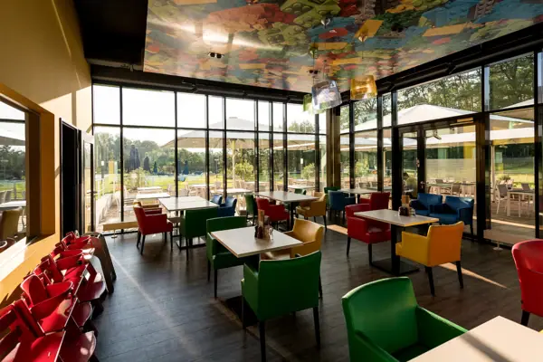A restaurant with colourful chairs and tables.