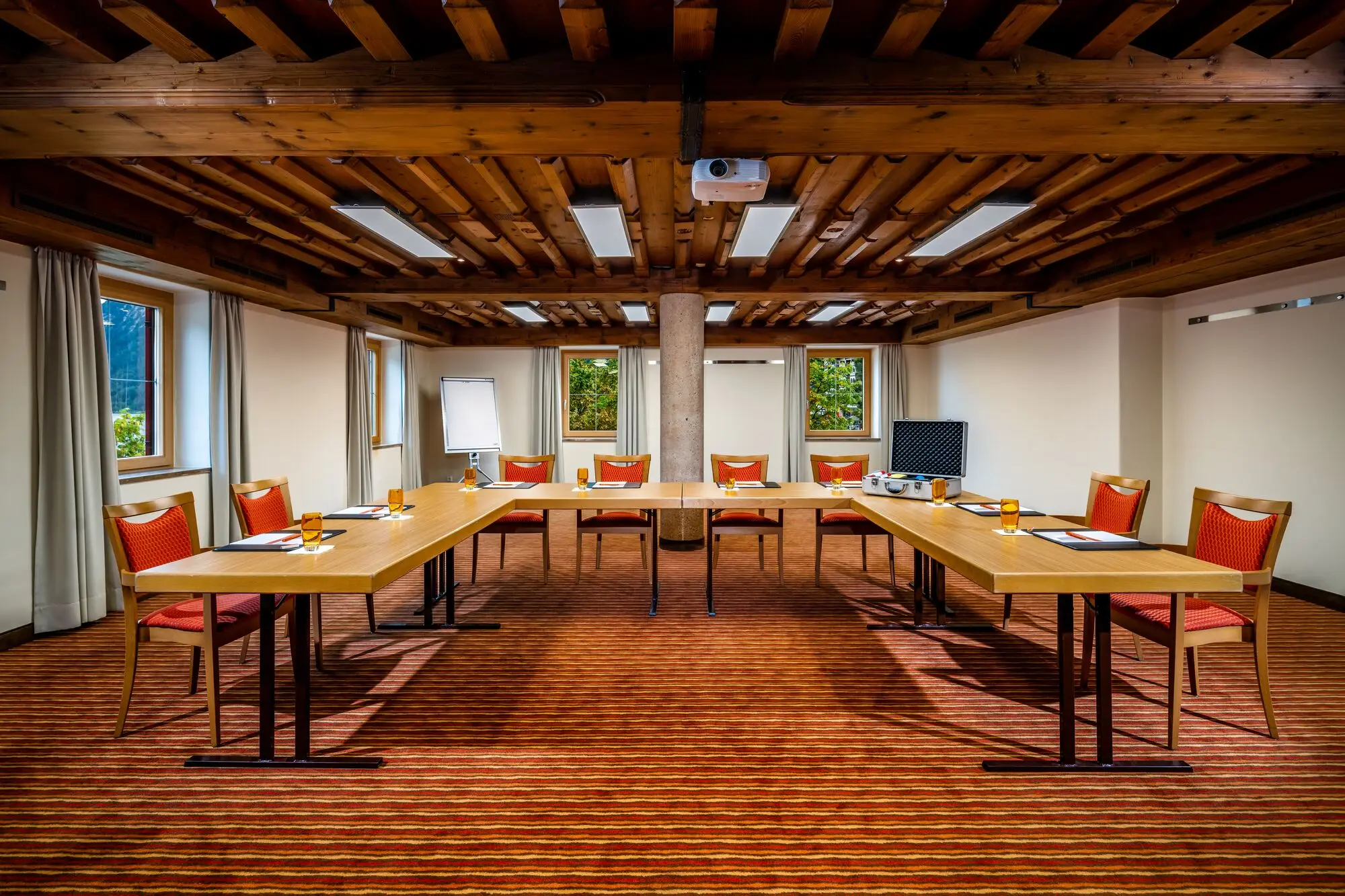 Conference area with U-shaped tables, chairs and windows.