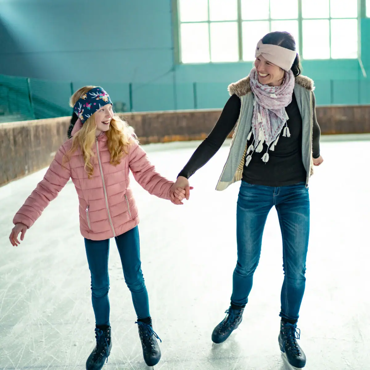 Ice skating A woman and a girl hold hands while skating.