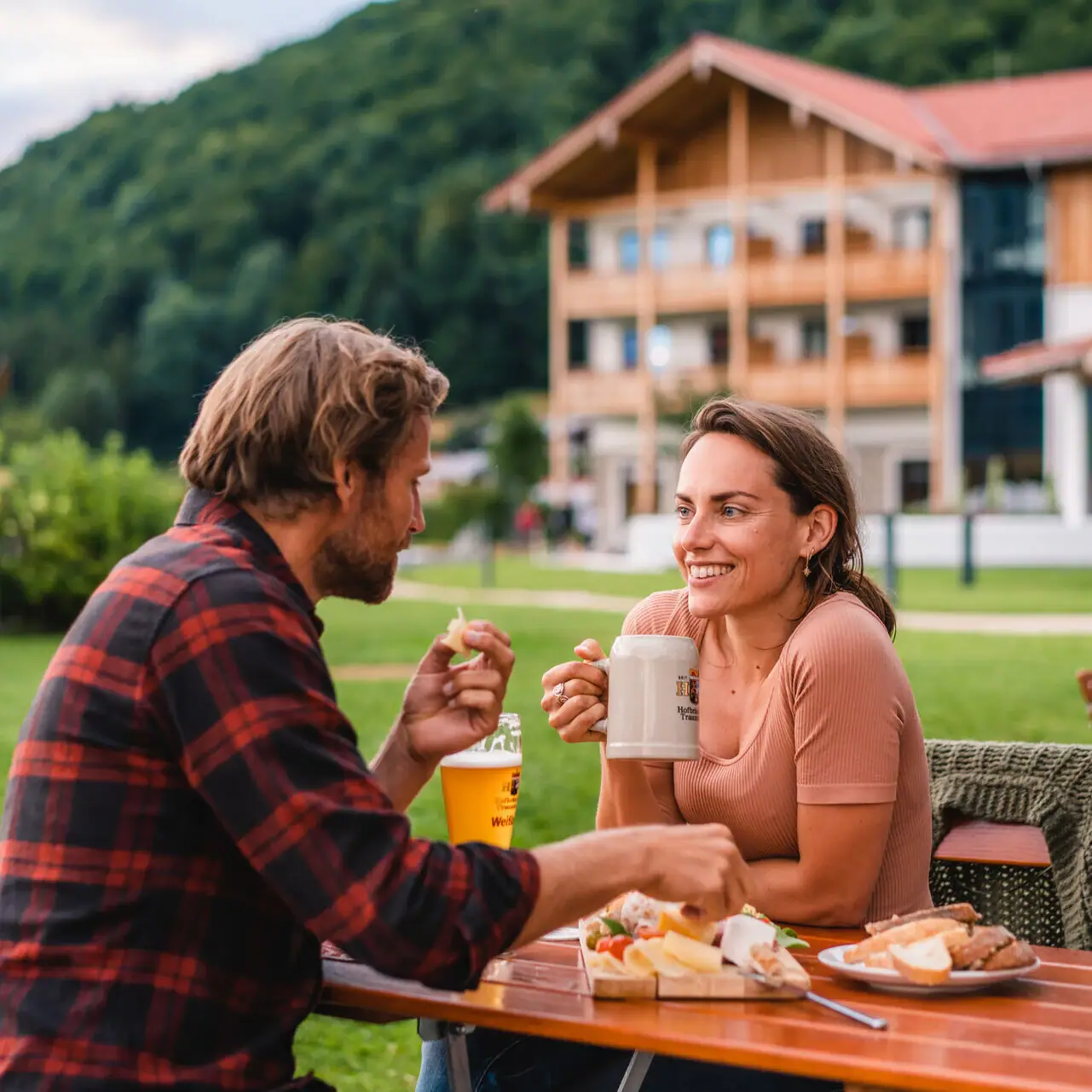 A man and a woman are sitting at a table with food and drinks.