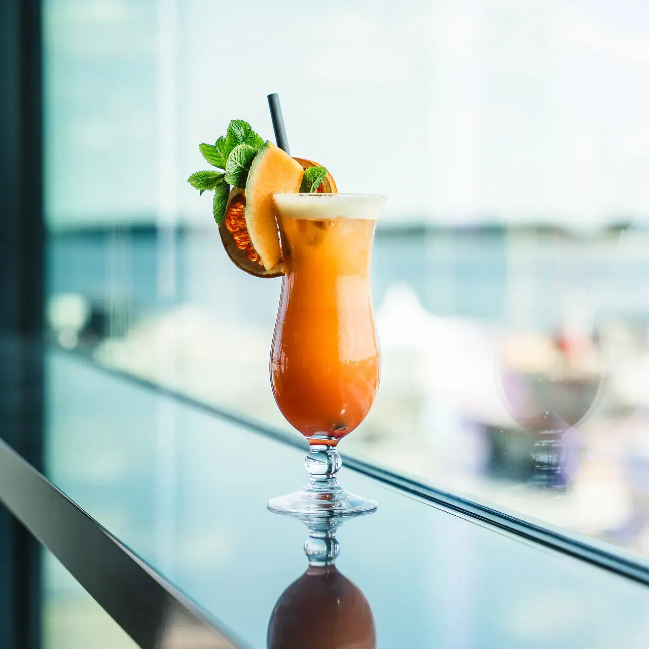 Cocktail A glass with a cocktail and a garnish on a table.