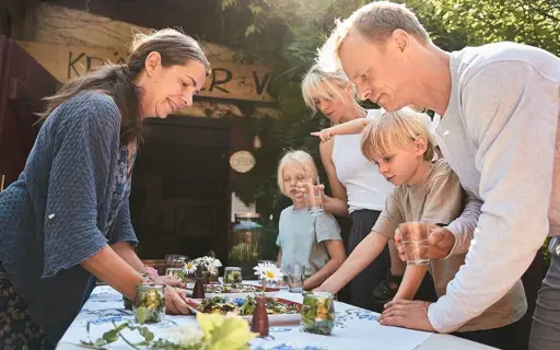 Three adults and two children are standing outside around a table with food and smiling.