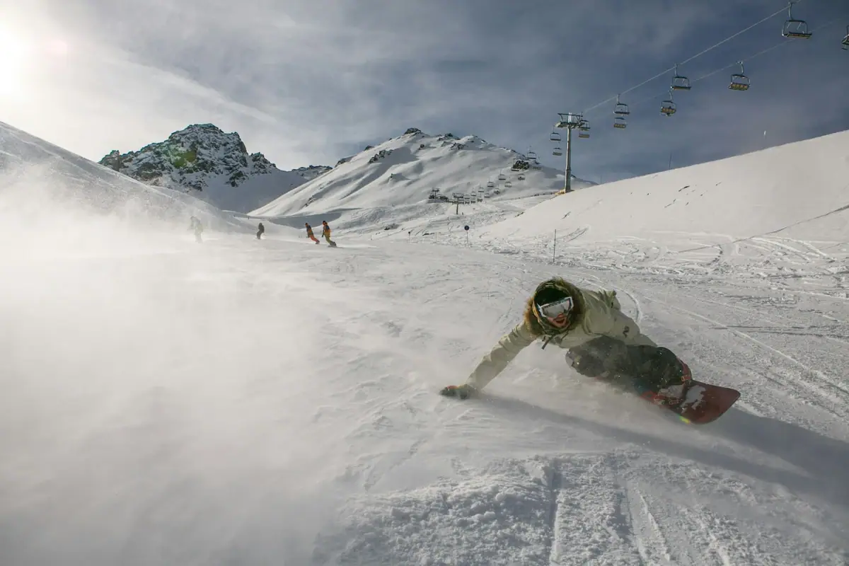 A person rides a snowboard down a snow-covered piste.