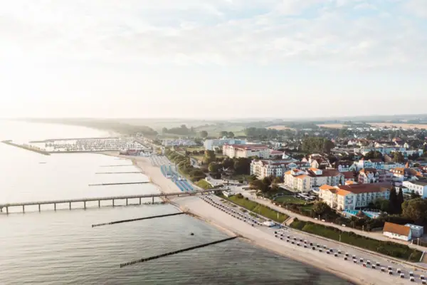 A-ROSA Ostseehotel Kühlungsborn City next to a body of water from a bird's eye view with sky and clouds.