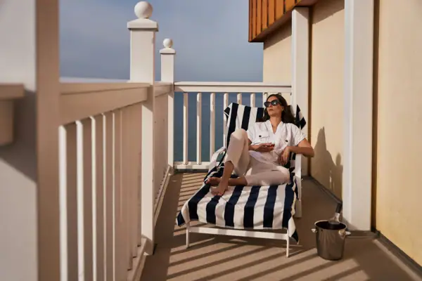 Room with a balcony A woman is sitting on a chair on a deck.