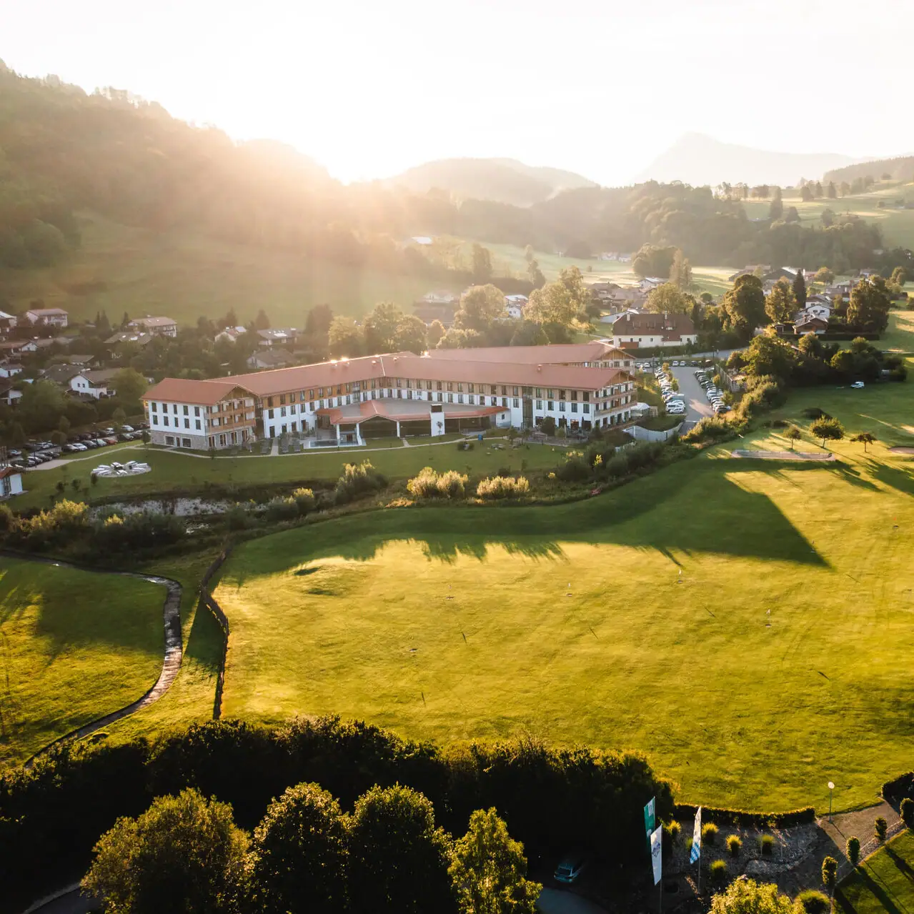 aja Hotel in Ruhpolding Large green field with a building and trees in the background.