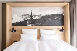 Junior Suite Mountain View Bed with white cushions and a picture above it