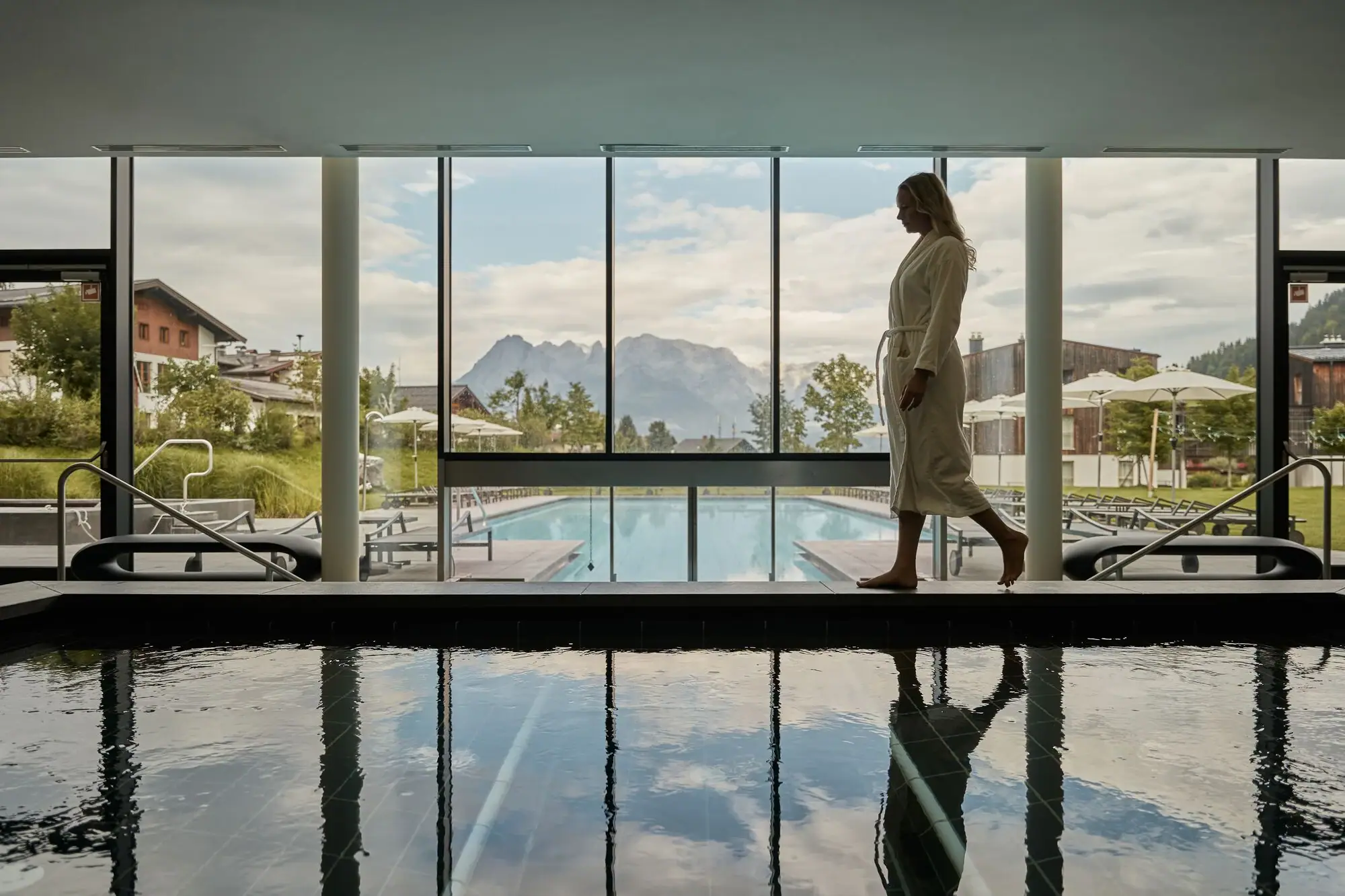 Woman walking by a pool with reflections on the water.