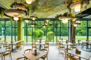 Ein Raum mit Tischen und Stühlen, Pflanzen hängen von der Decke.