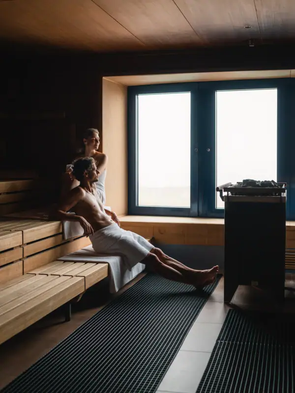 A man and a woman are sitting in a sauna.