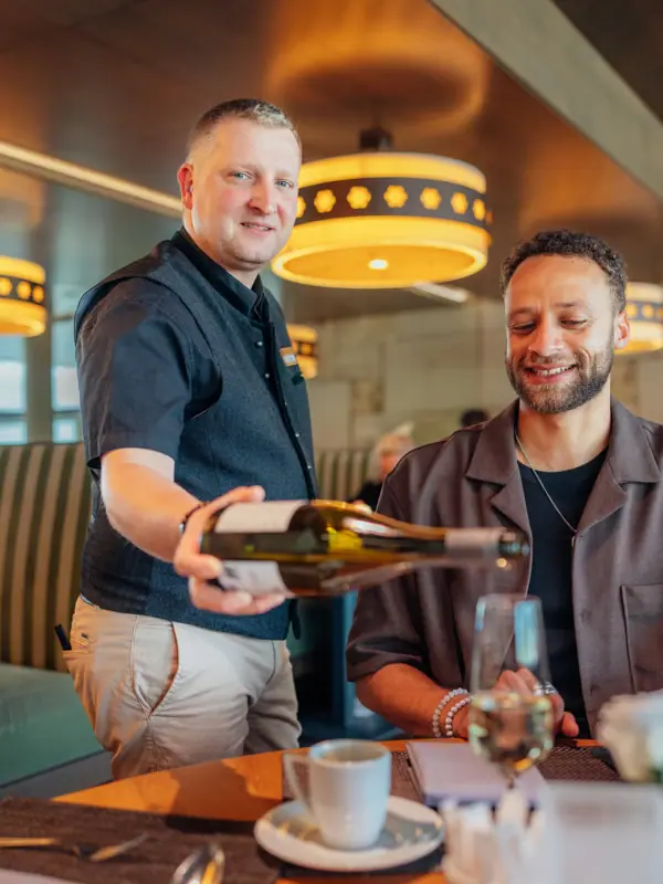 A man is pouring wine into a glass.