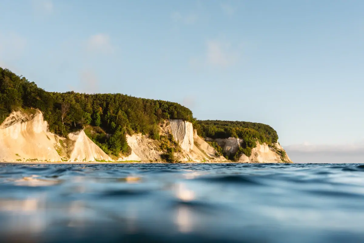 Body of water with cliff and trees in the background.