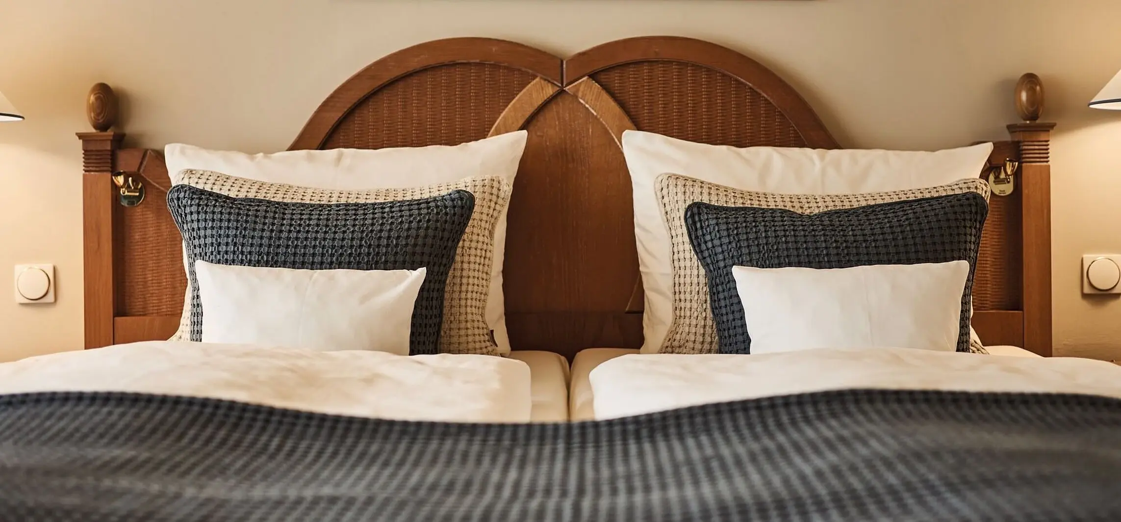 A cosy-looking bed with cushions and a picture on the wall above it, arranged in an interior.