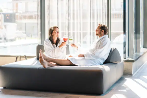 A man and a woman in bathrobes are sitting on a sofa.