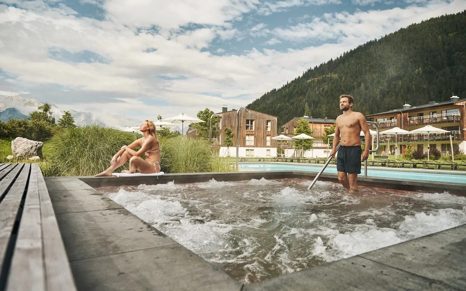 A man and a woman in an outdoor hot tub.