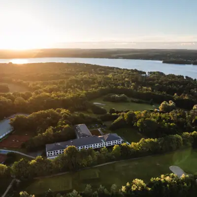 aja Bad Saarow Der Scharmützelsee von oben mit dem aja Bad Saarow und Bäumen im Vordergrund.