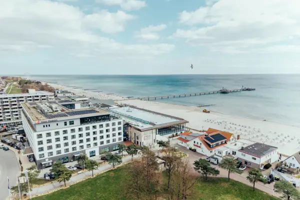 aja Hotel Grömitz A beach with buildings and a pier in the foreground.