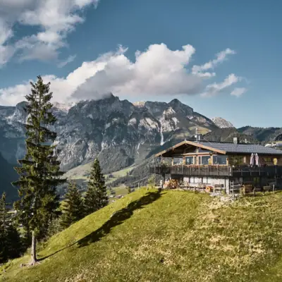 Werfenweng mountains A hut on a hill in front of a mountain panorama.