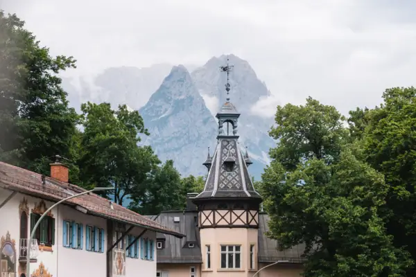 A building with a tower and trees in front of mountains.