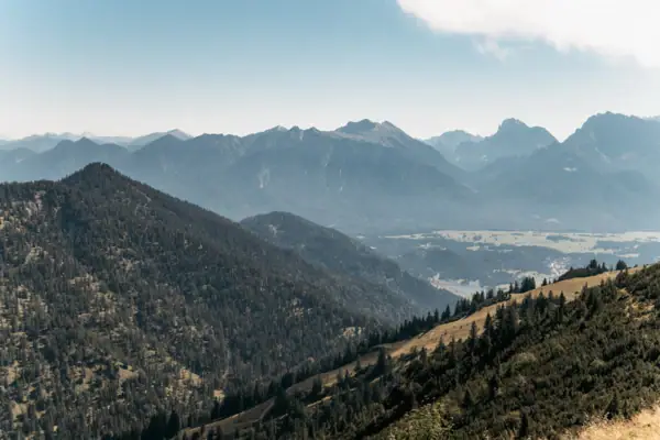 Mountain range with trees and a lake in the foreground.