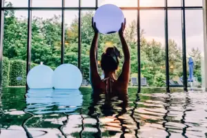 A woman in the pool is holding a ball.