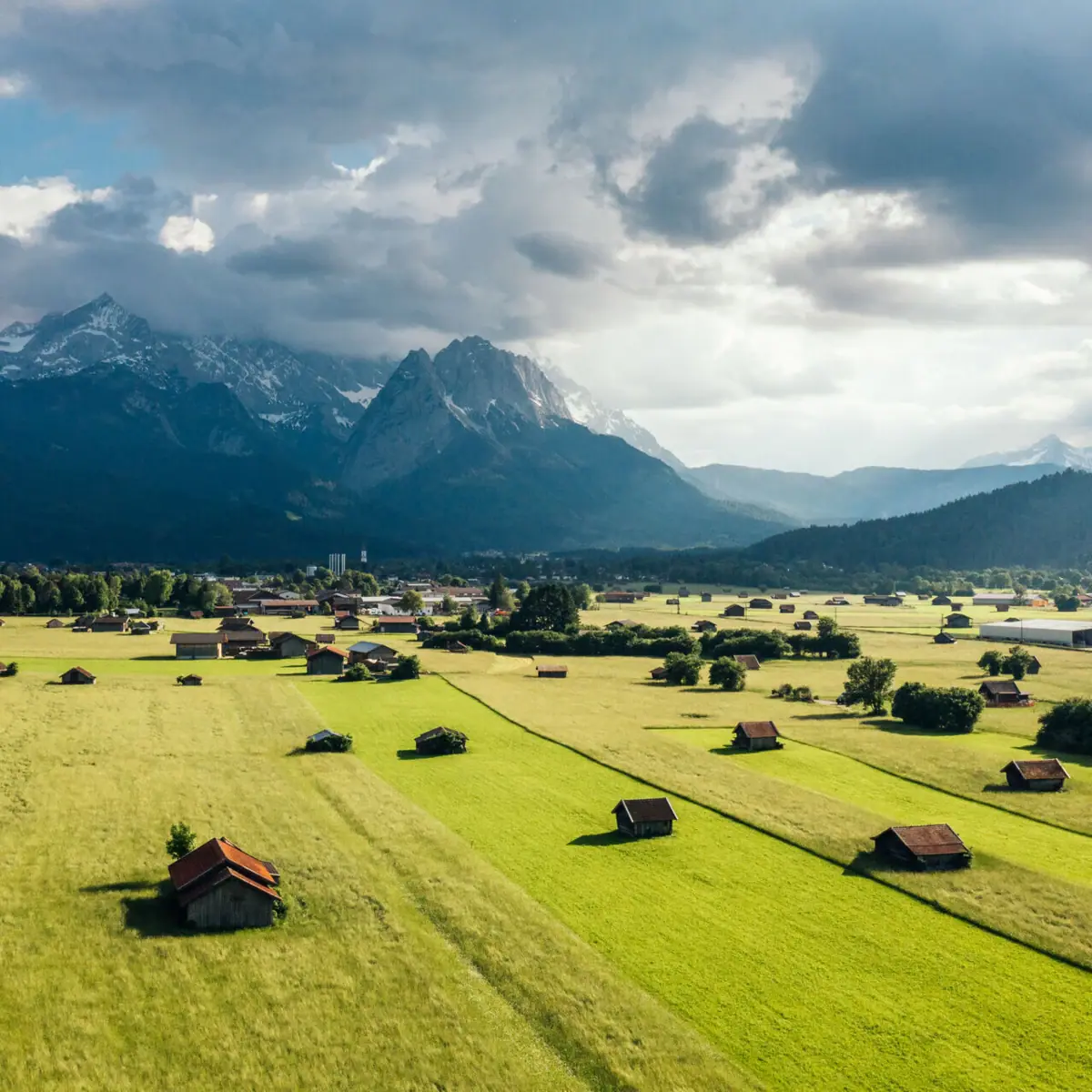 Green field with buildings and the Zugspitze in the background