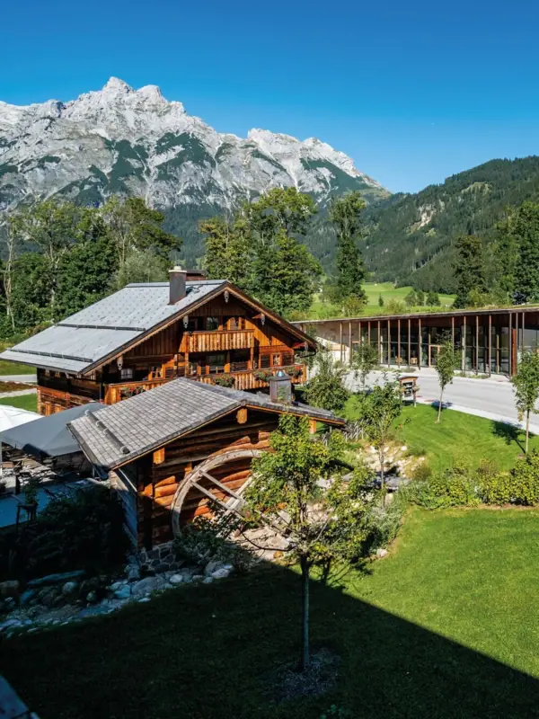 A building with a glass roof and a road, with mountains in the background.