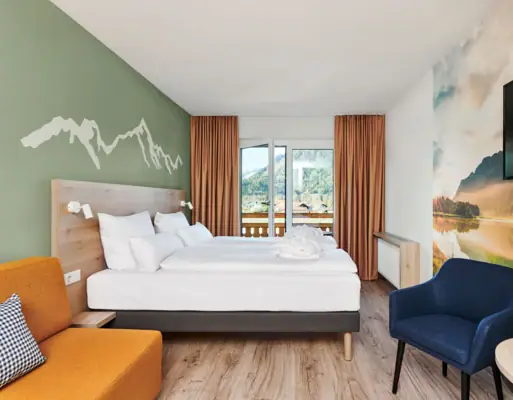 Double room with balcony aja Ruhpolding A room with a bed and a chair.