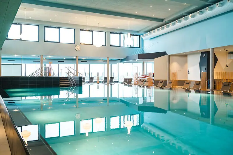 Large indoor pool with chairs and stairs.