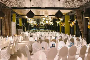 A large hall with lots of tables and chairs with white covers.