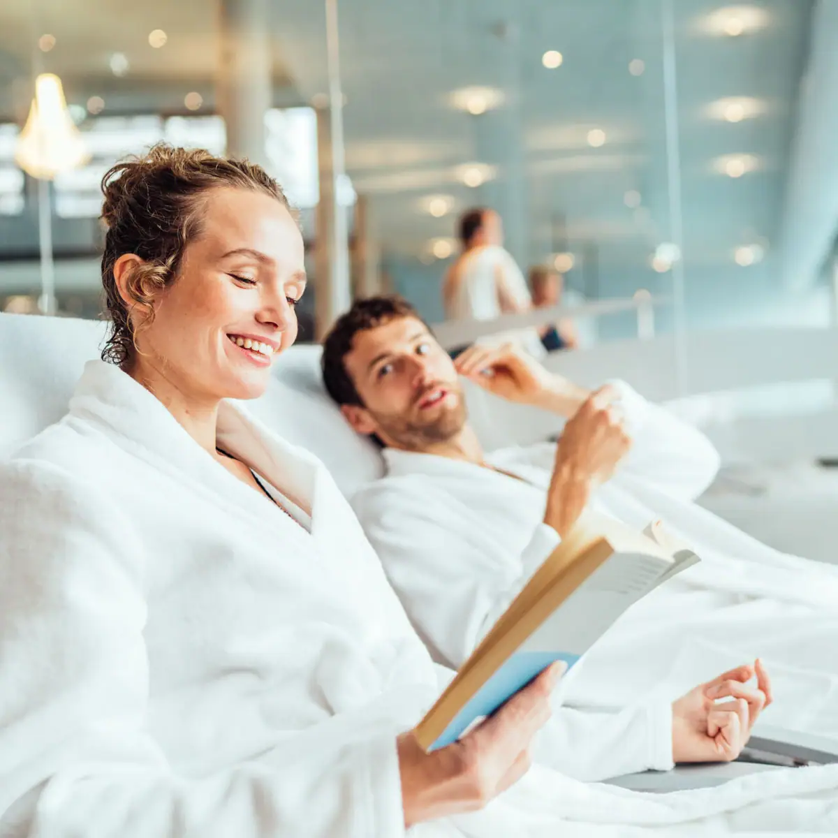 Relaxation in the aja SPA A man and a woman in bathrobes are reading a book.