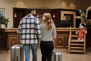 A man and a woman with luggage in the hotel lobby.