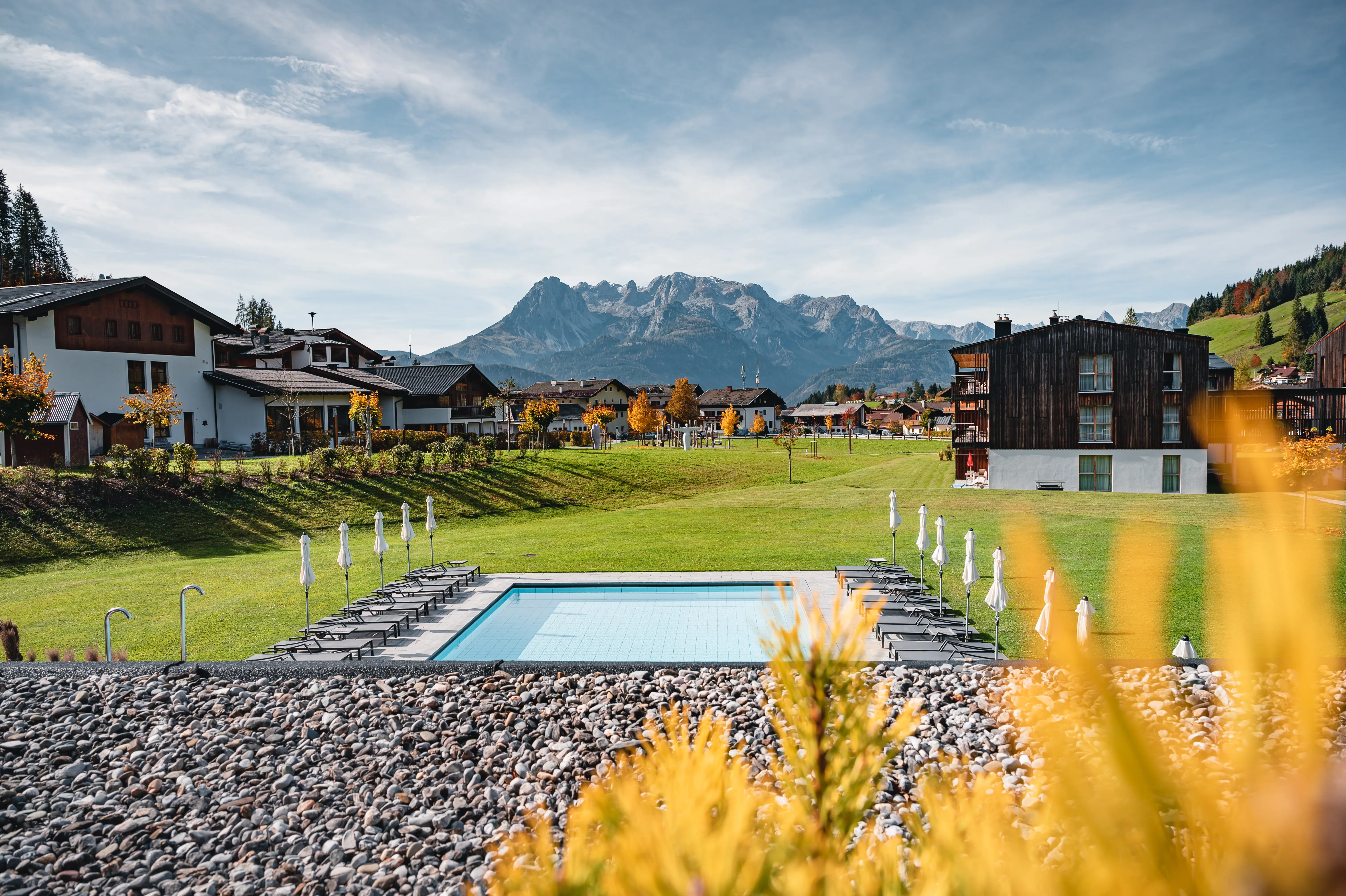 View Werfenweng A pool in a grassy area with mountains in the background.