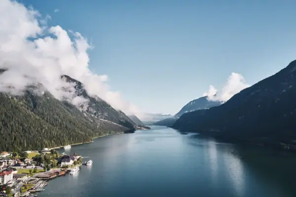 Lake Achensee A body of water with a house and mountains in the background.
