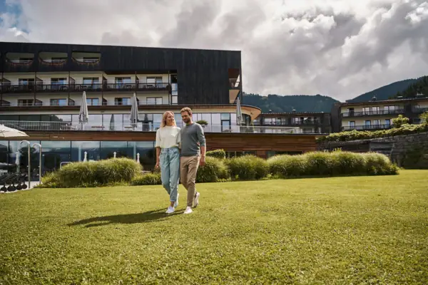 A man and a woman are walking on a lawn.