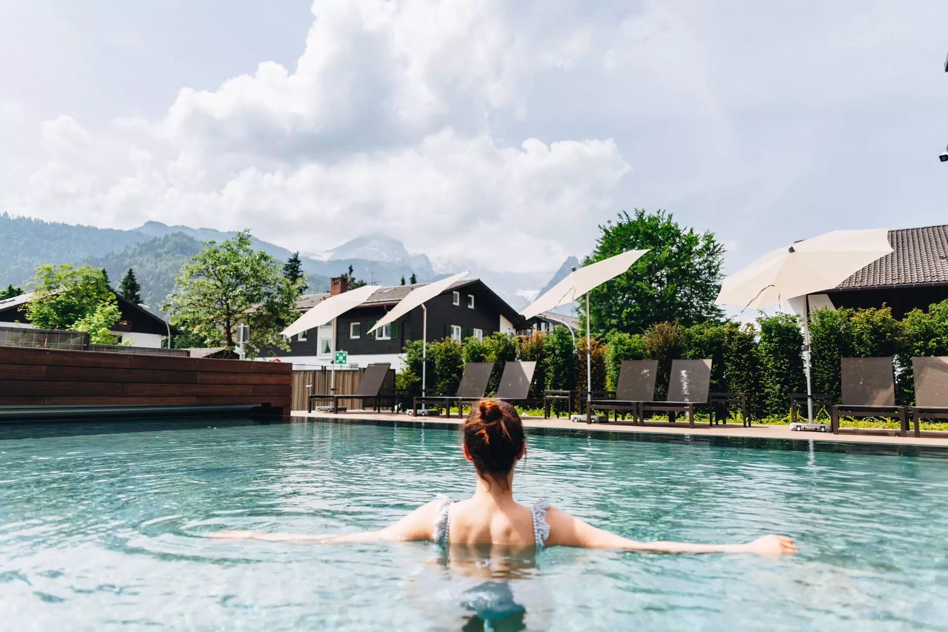 A woman swimming in a swimming pool against a mountain backdrop