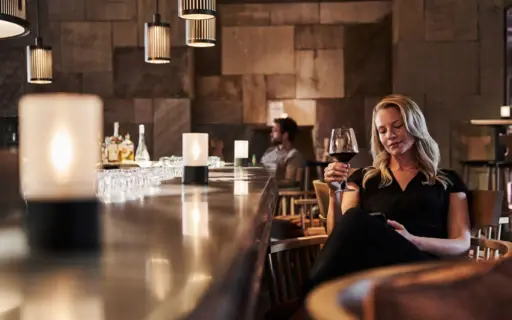 Woman sitting at a bar holding a glass of wine.