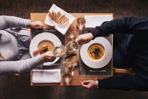 Eine Gruppe von Menschen sitzt an einem Tisch mit Tellern und Weingläsern.