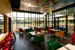 A restaurant with colourful chairs and tables.