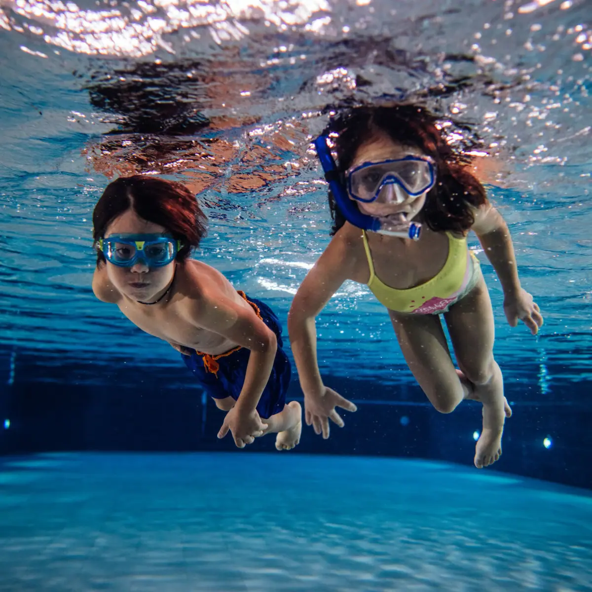 Swimming course Two children swimming underwater in a pool.