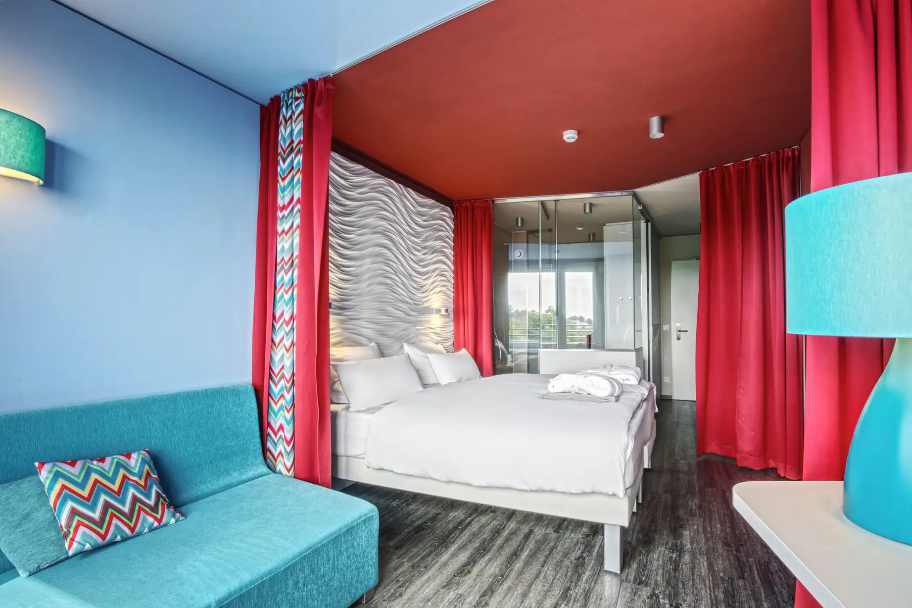 A room with a bed and a blue sofa.