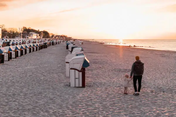 A man and a child walk along the beach.