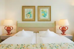 Junior suite facing the lake with balcony A bed with two lamps and two pictures on the wall.