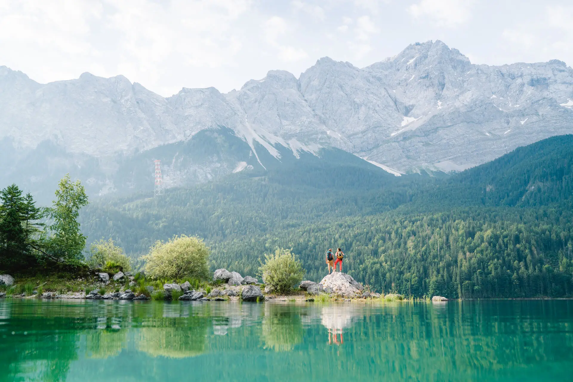 Eibsee People standing on a rock in front of a lake.