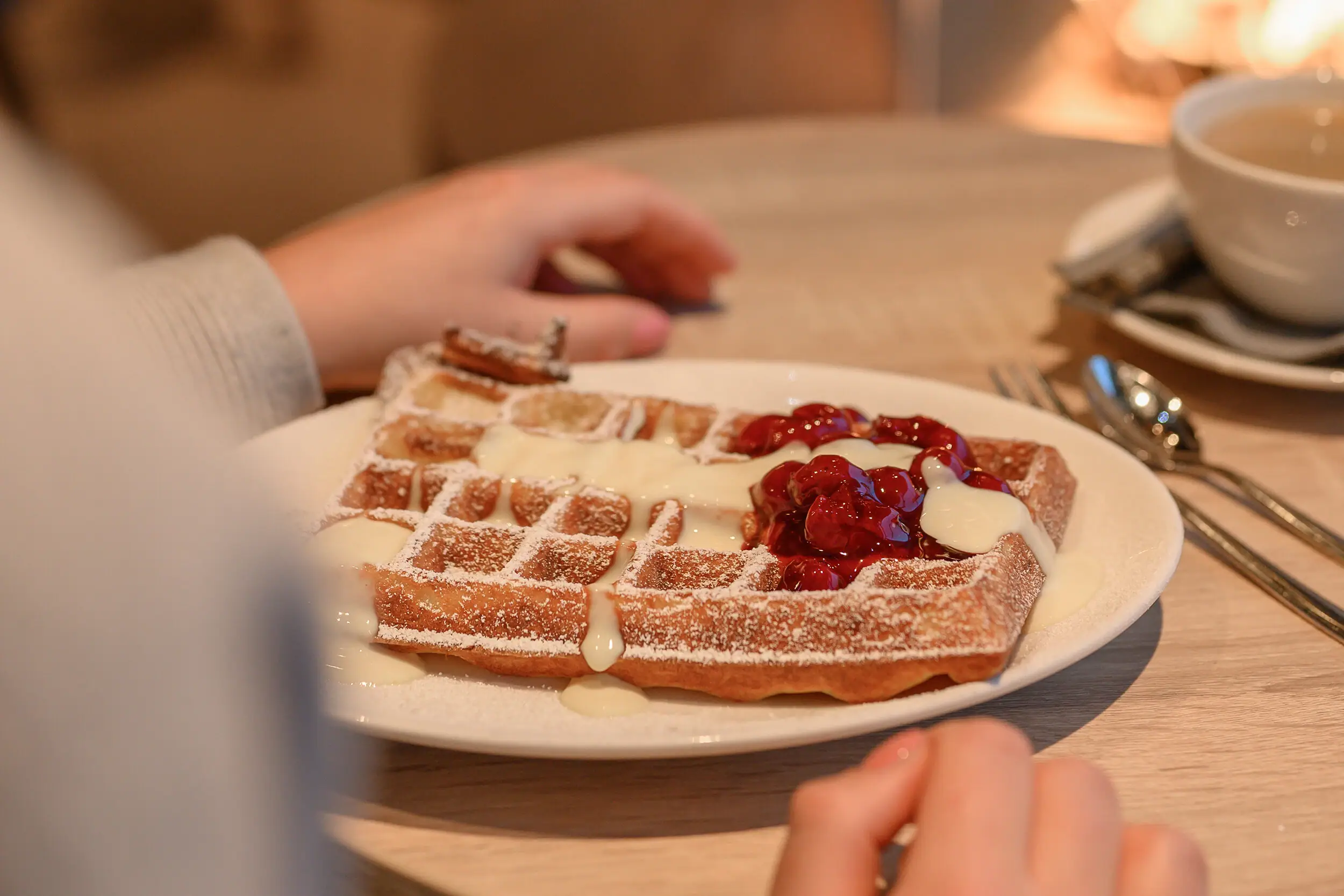 A plate of waffles and jam next to a cup of coffee.