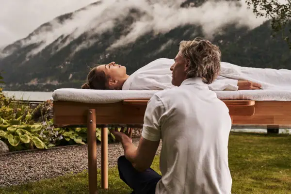 Massage Ein Mann kniet auf einem Tisch, auf dem eine Frau liegt.