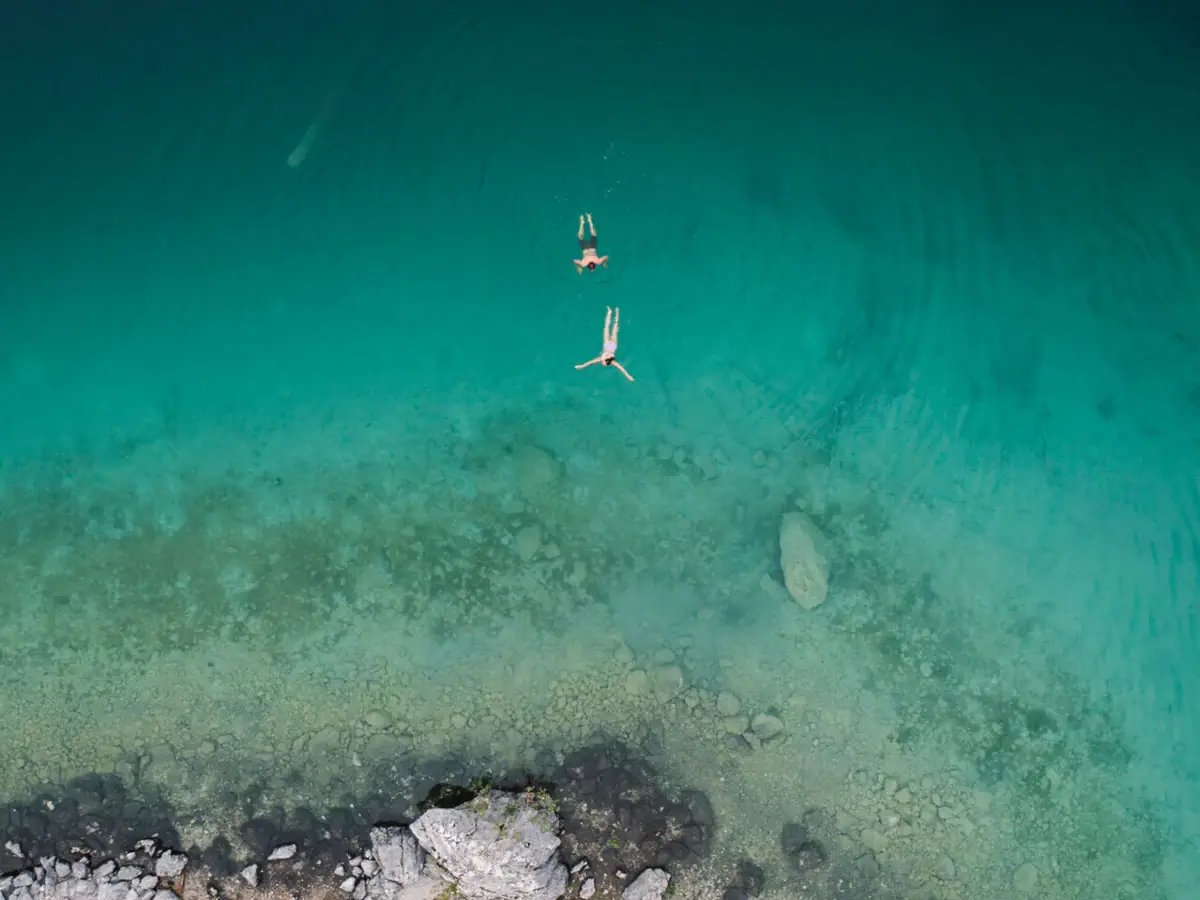 Two people swim in the turquoise-coloured water.