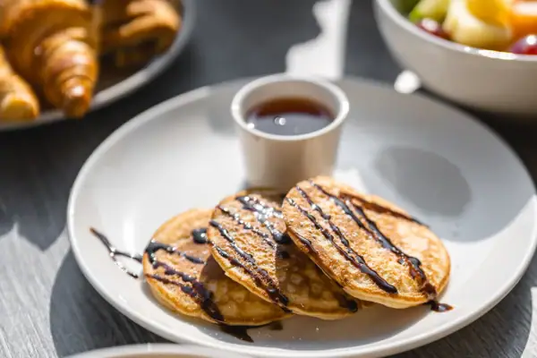 Egg dishes A plate with pancakes and syrup and a cup with syrup.