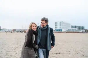 A man and a woman are walking along the beach.